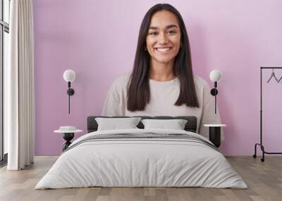 Young hispanic woman standing over pink background with a happy and cool smile on face. lucky person. Wall mural