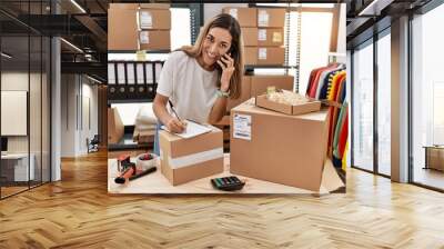 Young hispanic woman talking on the smartphone working at store Wall mural