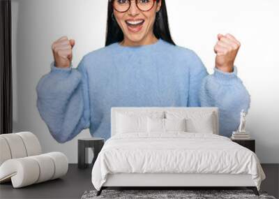 Young hispanic woman wearing casual clothes and glasses celebrating surprised and amazed for success with arms raised and open eyes. winner concept. Wall mural