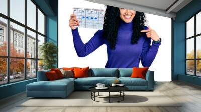 Young hispanic woman with curly hair holding rainy weather calendar pointing finger to one self smiling happy and proud Wall mural