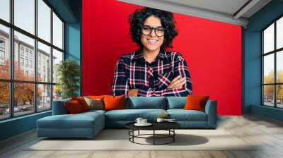 Young hispanic woman with curly hair wearing casual clothes and glasses happy face smiling with crossed arms looking at the camera. positive person. Wall mural