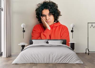 Young hispanic woman with curly hair wearing casual sweatshirt thinking looking tired and bored with depression problems with crossed arms. Wall mural