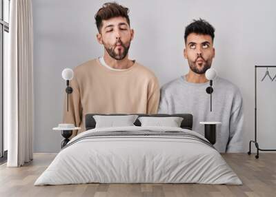 Young homosexual couple standing over white background making fish face with lips, crazy and comical gesture. funny expression. Wall mural