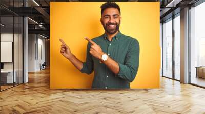 Young indian businessman wearing elegant shirt standing over isolated white background smiling and looking at the camera pointing with two hands and fingers to the side. Wall mural