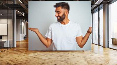 Young indian man wearing t-shirt standing over isolated white background smiling showing both hands open palms, presenting and advertising comparison and balance Wall mural