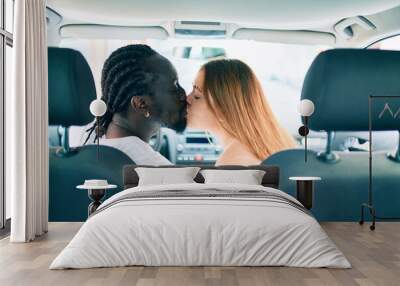 Young interracial couple smiling happy and kissing at the car. Wall mural