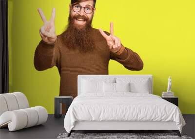 Young irish redhead man wearing casual clothes and glasses smiling with tongue out showing fingers of both hands doing victory sign. number two. Wall mural