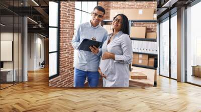 Young latin couple ecommerce business workers working at office Wall mural