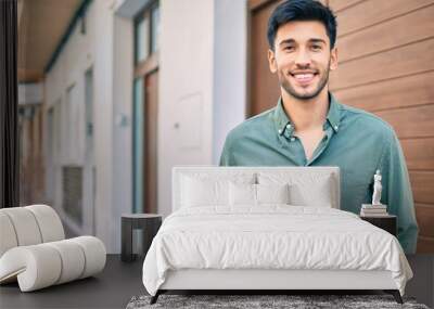 Young latin man smiling happy walking at the city. Wall mural