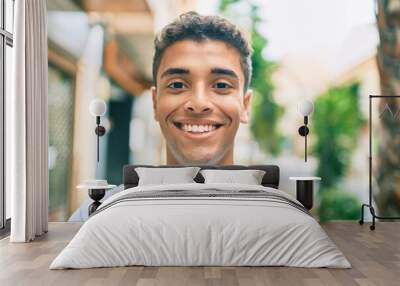 Young latin man smiling happy walking at the city. Wall mural