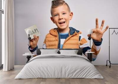 Young little caucasian kid asking for help on a paper note as violence victim message doing ok sign with fingers, excellent symbol Wall mural