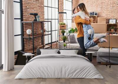 Young man and woman couple hugging each other standing at new home Wall mural