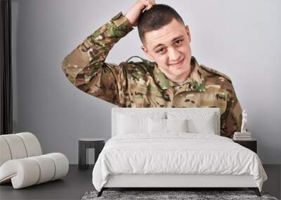 Young man wearing camouflage army uniform confuse and wonder about question. uncertain with doubt, thinking with hand on head. pensive concept. Wall mural