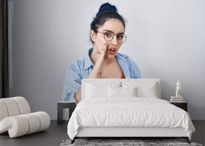 Young modern girl with blue hair standing over white background hand on mouth telling secret rumor, whispering malicious talk conversation Wall mural