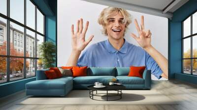 Young modern man standing over isolated background showing and pointing up with fingers number eight while smiling confident and happy. Wall mural