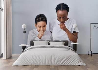 Young mother and son standing together over white background feeling unwell and coughing as symptom for cold or bronchitis. health care concept. Wall mural