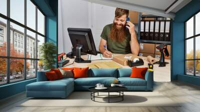 Young redhead man business worker talking on the smartphone at office Wall mural