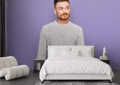 Young redhead man wearing casual winter sweater smiling looking to the side and staring away thinking. Wall mural