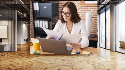 Young woman business worker using laptop reading document at office Wall mural