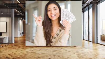 Young woman holding 50 dollars bank notes very happy pointing with hand and finger to the side Wall mural