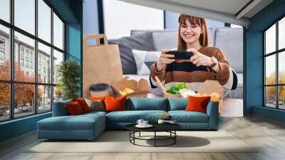 Young woman make photo by the smartphone to take away food at home Wall mural