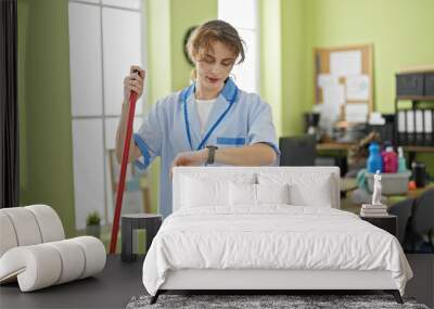 Young woman professional cleaner looking watch cleaning floor at the office Wall mural