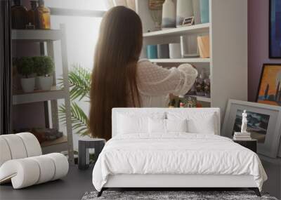 Young woman shopping in a home decor store, surrounded by various decorative items and plants, wearing a white blouse and looking at shelves filled with items Wall mural