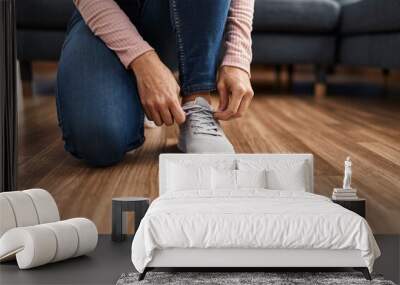 Young woman tying shoelace at home Wall mural