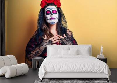 Young woman wearing day of the dead costume over yellow smiling with hands on chest with closed eyes and grateful gesture on face. health concept. Wall mural