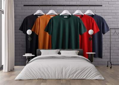 Collection of colorful t-shirts on hangers against a brick wall background, showcasing various styles and vibrant hues for casual wear. Wall mural