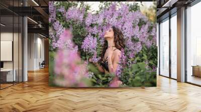 a beautiful girl with makeup and hair styling in underwear stands in a garden with lilacs on a summer evening Wall mural