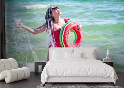 A cheerful middle-aged woman with a watermelon wedge swimming circle swimming in a sea. The concept of leisure and entertainment Wall mural