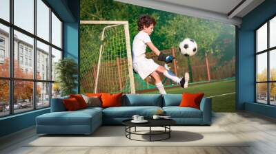 Boys in white sportswear running on soccer field. Young footballers dribble and kick football ball in game. Training, active lifestyle, sport, children activity concept. selective focus Wall mural