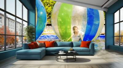 Young girl playing inside a floating water walking ball. Wall mural