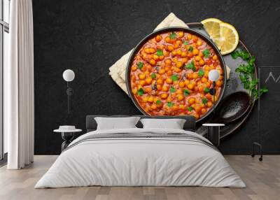 Chana Masala or Chole in black bowl on dark slate table top. Indian cuisine veg chickpeas curry dish. Asian spicy vegetarian food and meal. Copy space. Top view Wall mural