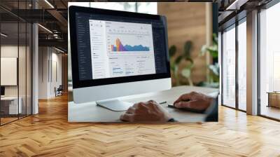 A man is working on a computer with a data analytics dashboard. Wall mural