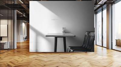 A minimalist table with two chairs in a modern cafe or restaurant, lit by a ray of sunlight. Wall mural