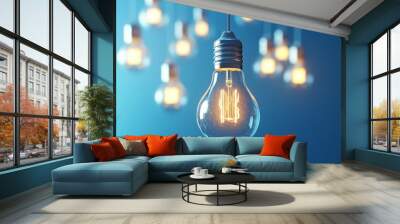 A single, glowing light bulb hangs from a wire against a blue background, with other bulbs blurred in the background. Wall mural