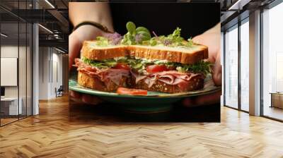 Female hand holding plate with delicious ham sandwich Wall mural