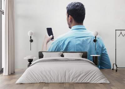 Back view of a man using mobile phone wearing blue shirt Wall mural