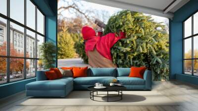 Man in coveralls loading a fresh cut Christmas tree onto a wagon Wall mural