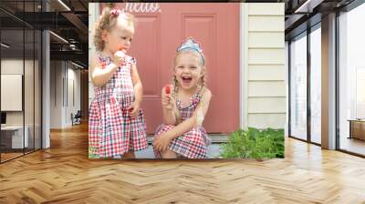 Two cute little girls eating frozen fruit pops in summer Wall mural