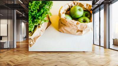 apples and greens in a paper bag with a sign for recycling and recycling. ecotara . the theme of ecology . isolated on a bright yellow background Wall mural