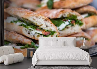 Closeup of fresh display of stacked pile of panini bread, mozzarella melted cheese, vegetarian italian tomatoes, basil lettuce in store, shop, cafe buffet catering sandwiches Wall mural