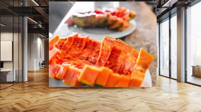 Closeup of large Caribbean red ripe papaya fruit sliced with fresh orange red colorful flesh cut in half on bar counter with two plates for romantic tropical meal Wall mural