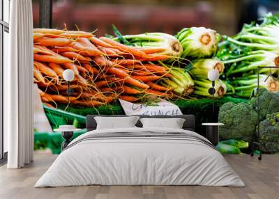 Closeup of many green and orange carrots with greens in farmer's market on display at stall bunches and price in English pounds in London Wall mural