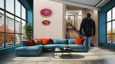 Closeup of sign at inn hotel motel with number for non-smoking room and man traveler walking at corridor at night Wall mural