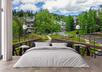 Pedestrian footbridge bridge on village loop hiking trail in Beaver Creek ski resort of Vail near Avon, Colorado in summer with aspen trees forest and homes houses condo buildings Wall mural