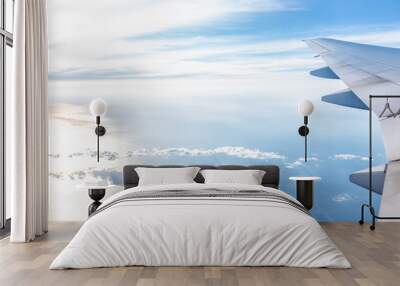 White airplane in blue sky with view from window high angle during sunny day with plane wing and sun setting above horizon with light path Wall mural