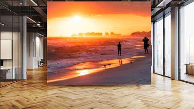 Young couple looking at dramatic orange red sunset in Santa Rosa Beach, Florida with Pensacola coastline coast skyline in panhandle with ocean gulf mexico waves Wall mural